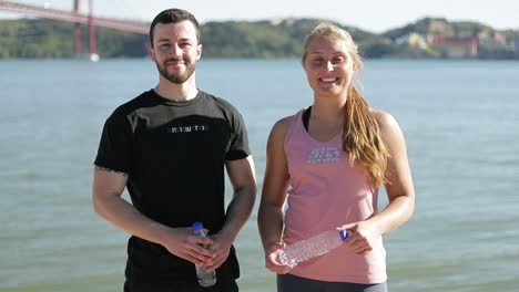 Happy-smiling-sporty-couple-standing-on-riverside.